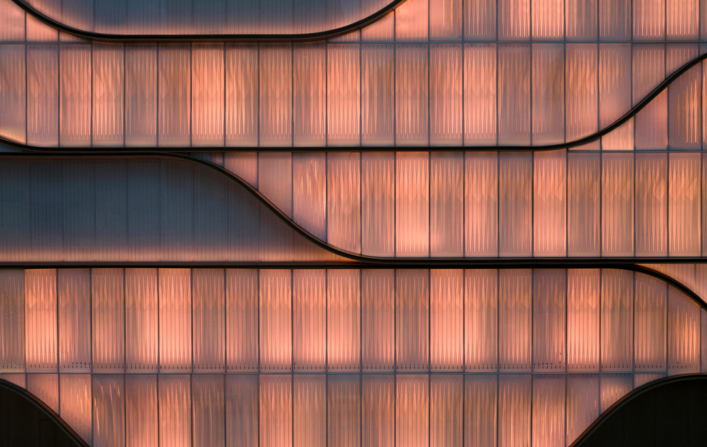 The SKP Wuhan façade uses layered translucent panels, moiré-like texture and flowing curve lines to create a softly illuminated architectural surface that shifts with light, reflection and movement.