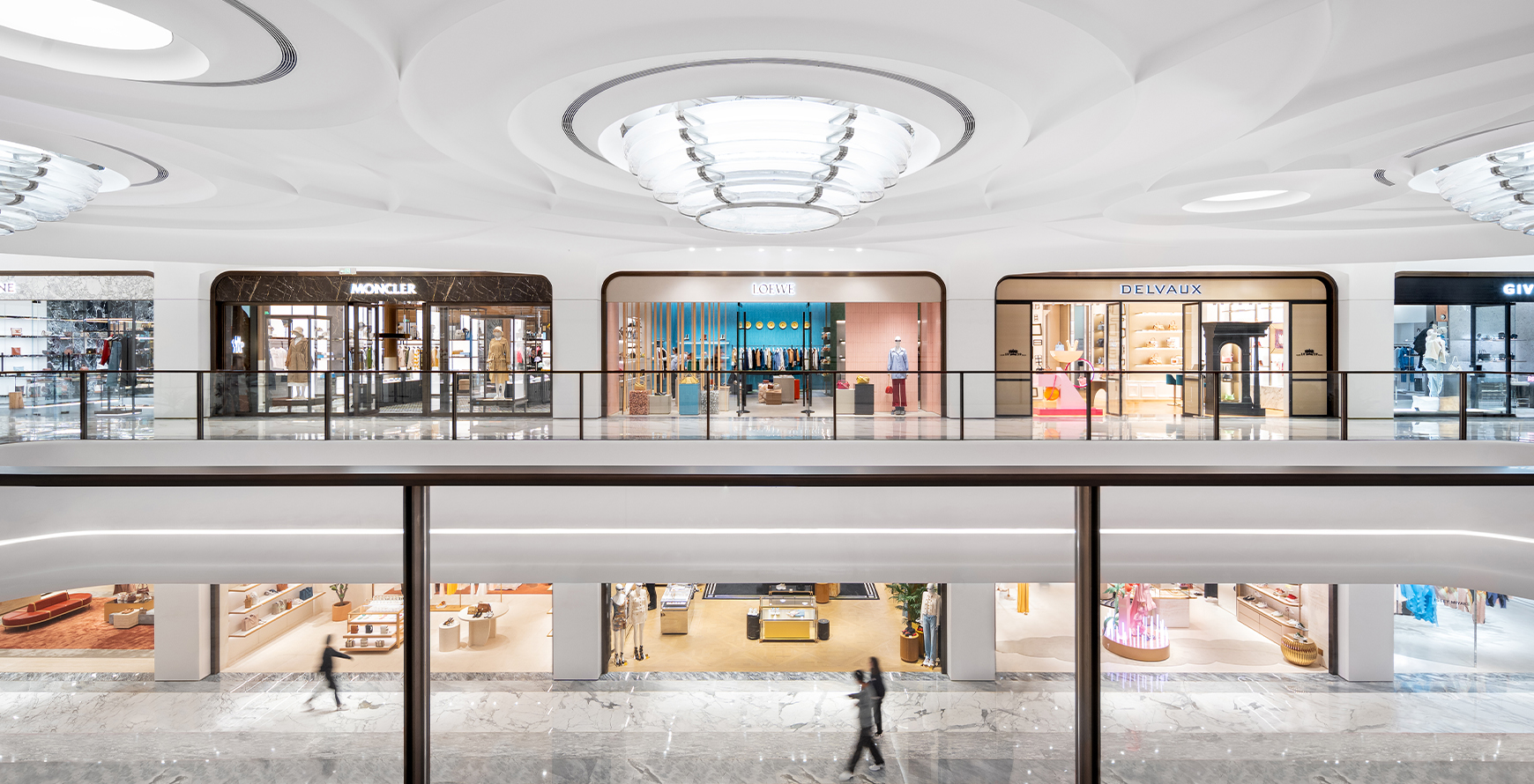 SKP Chengdu luxury retail atrium with two levels of designer storefronts, sculpted white ceilings and large circular chandeliers.