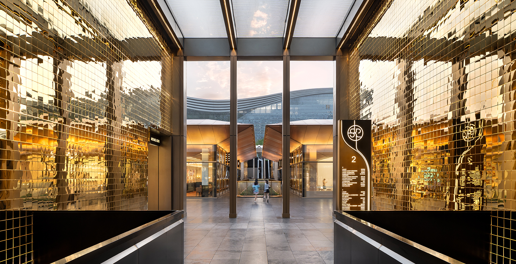 Golden baffle-lined passage at SKP Chengdu, framing views toward the retail park and New Century Global Centre.