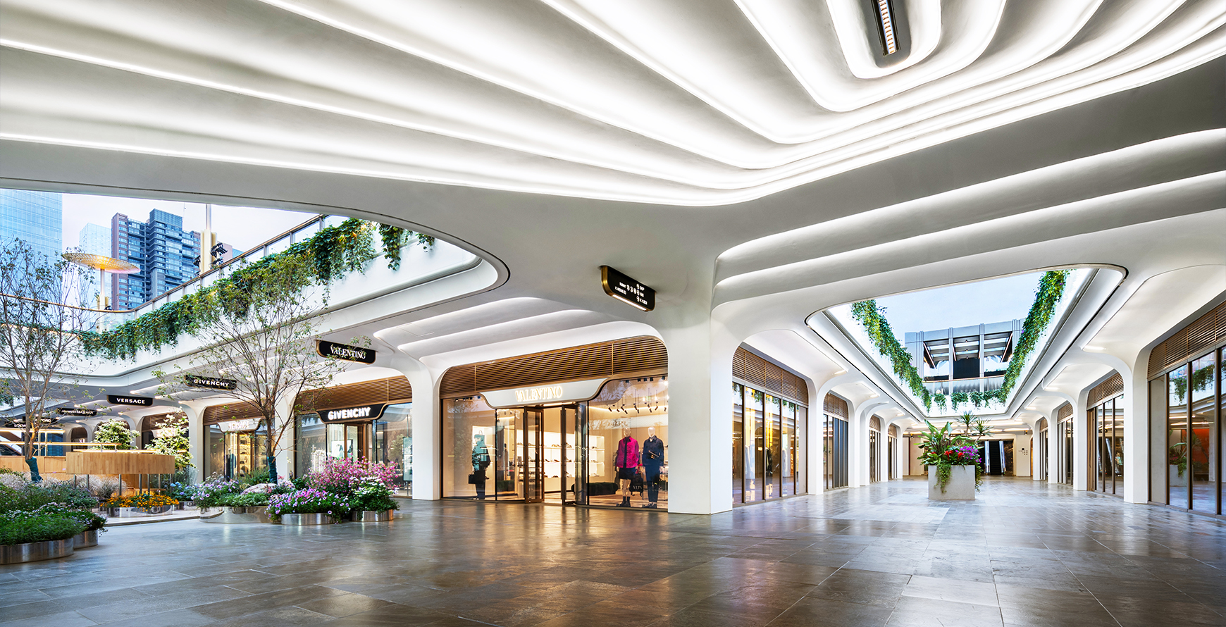 SKP Chengdu open-air retail walkway with curved white canopies, planted terraces and luxury storefronts including Valentino and Givenchy.