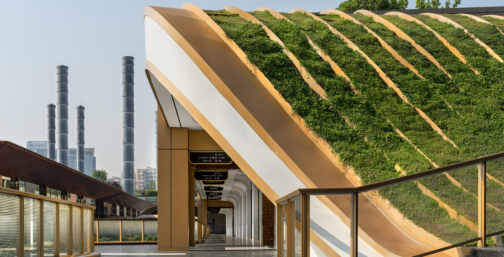 SKP Chengdu retail park detail showing a planted green roof curve, bronze-toned architectural edges and covered pedestrian walkway.