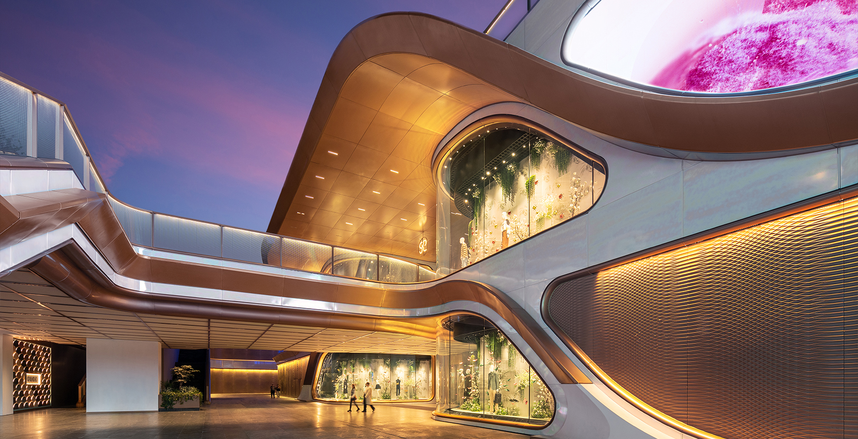 SKP Chengdu retail park façade at dusk, with curved bronze-toned architecture, illuminated storefronts and layered pedestrian routes.