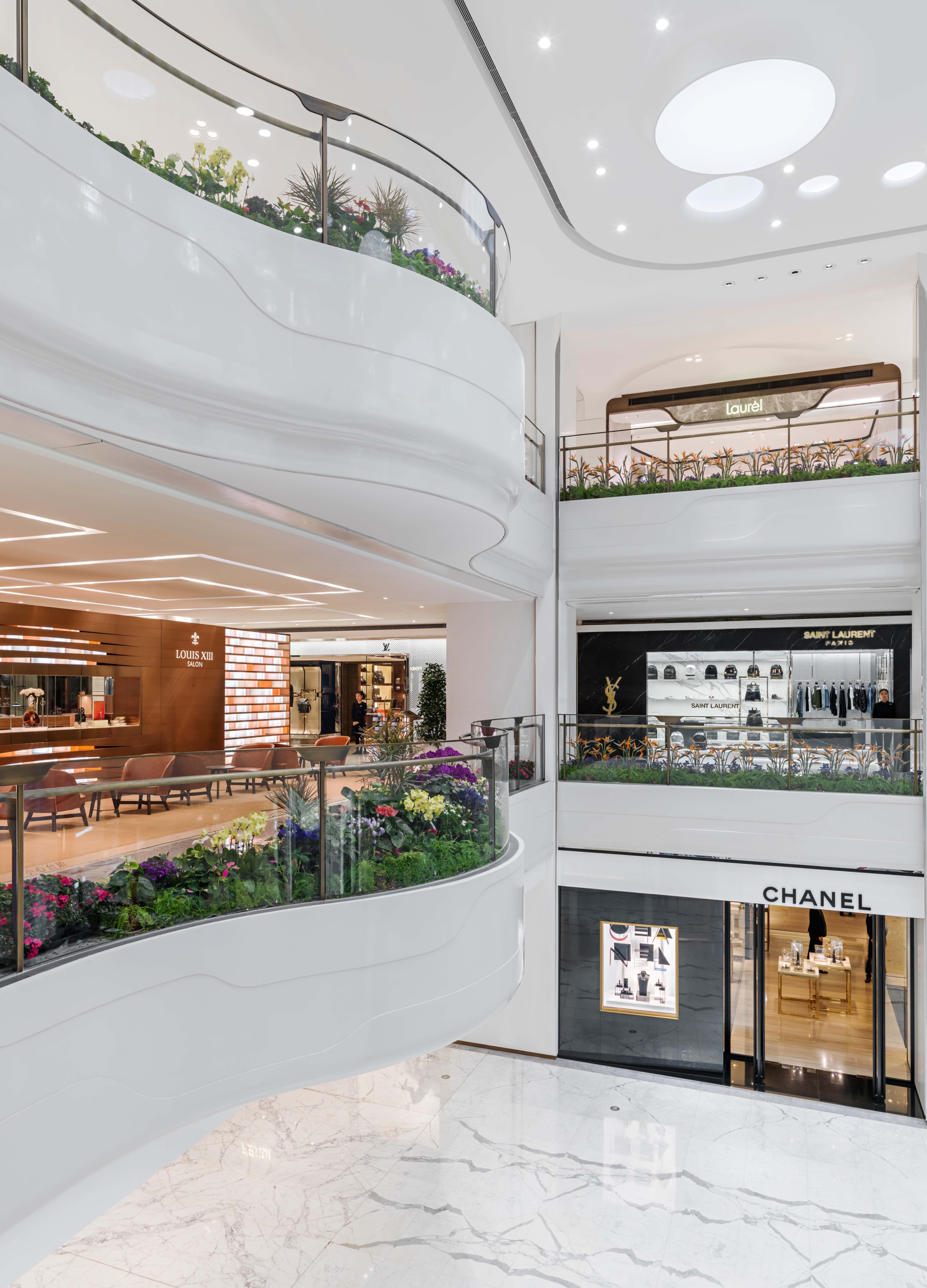 The SKP Beijing atrium detail shows the SKP Curve shaping the department store’s interior architecture, with planted balconies, soft white balustrades and luminous ceiling forms creating a calm, vertically layered luxury retail environment.
